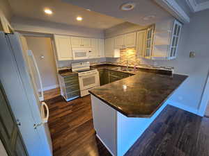 Dual tone kitchen featuring open shelves, white appliances, a peninsula, tasteful backsplash, and recessed lighting