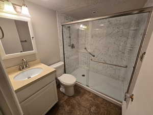 Bathroom featuring vanity, a stall shower, and a textured ceiling