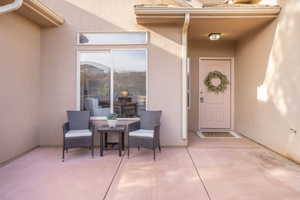 View of exterior entry featuring stucco siding and a patio area
