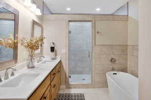 Full bath with a soaking tub, a shower stall, double vanity, light tile patterned floors, and recessed lighting