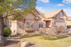 View of front facade with stucco siding, a front lawn, a garage, and a tile roof