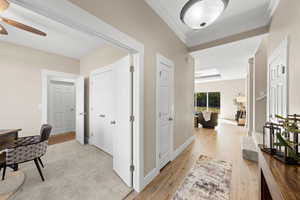 Corridor featuring light wood-style floors and crown molding