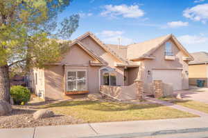Traditional-style home featuring concrete driveway, stucco siding, a garage, a front yard, and a tiled roof