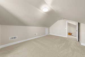 Additional living space featuring baseboards and light carpet