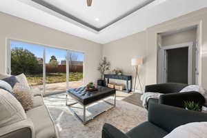 Living room featuring a tray ceiling, wood finished floors, a ceiling fan, and recessed lighting