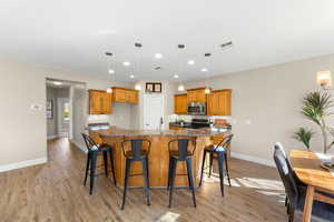 Kitchen featuring a kitchen breakfast bar, dark stone countertops, wood finish cabinets, and hanging light fixtures