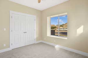 Unfurnished bedroom featuring light carpet, a closet, and ceiling fan