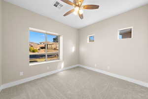 Carpeted spare room featuring baseboards and a ceiling fan