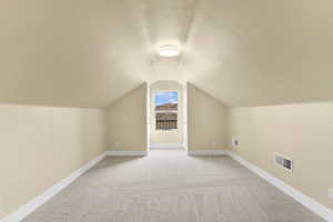 Bonus room featuring light colored carpet and a textured ceiling