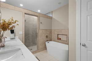 Bathroom with a shower stall, a freestanding bath, double vanity, tile walls, and recessed lighting