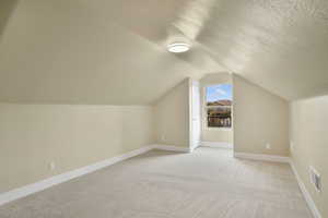 Bonus room featuring light carpet and a textured ceiling