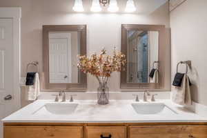 Bathroom featuring double vanity, a textured wall, and an enclosed shower