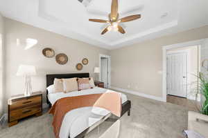 Bedroom with carpet, a tray ceiling, and a ceiling fan