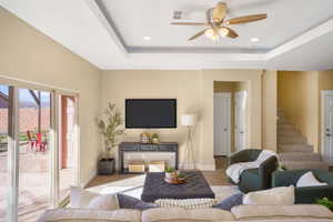Living room featuring wood finished floors, a tray ceiling, recessed lighting, and a ceiling fan