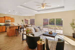 Living area with light wood-style flooring, hanging lights, healthy amount of natural light, and a ceiling fan