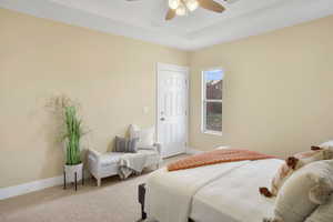 Carpeted bedroom with a raised ceiling and ceiling fan
