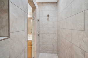 Full bath featuring vanity and tiled shower