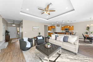 Living room featuring light wood-type flooring, a ceiling fan, and hanging lights