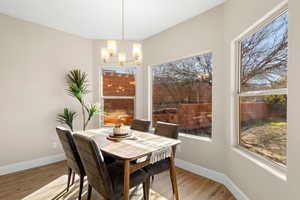Dining space featuring wood finished floors, a chandelier, and healthy amount of natural light