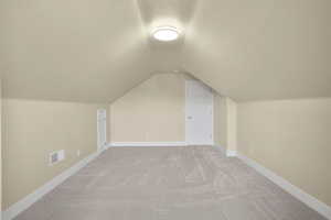 Bonus room with light colored carpet and baseboards