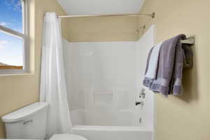 Bathroom featuring shower / bathtub combination with curtain and toilet
