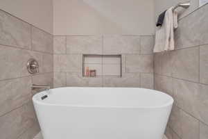 Full bathroom featuring a freestanding tub and tile walls
