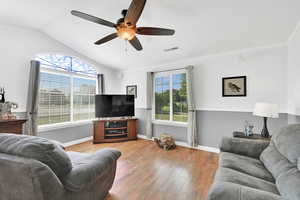 Living area featuring wood-type flooring, healthy amount of natural light, a ceiling fan, crown molding, and lofted ceiling