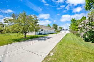 View of front of house with an outbuilding, a front lawn, a detached garage, and driveway