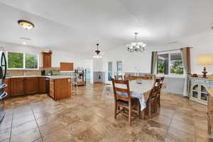 Dining area with a ceiling fan, plenty of natural light, vaulted ceiling, a chandelier, and french doors