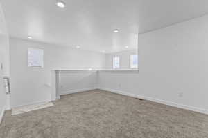 Empty room with a textured ceiling and light carpet