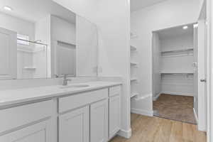 Bathroom featuring a spacious closet, vanity, light wood-type flooring, a shower, and recessed lighting