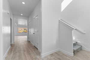 Corridor with light wood-style flooring and recessed lighting
