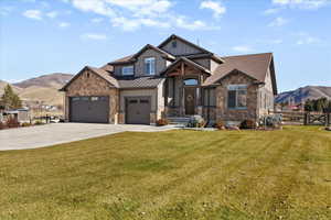 Craftsman house featuring a mountain view, stone siding, concrete driveway, board and batten siding, and a garage