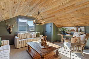Carpeted living area featuring a vaulted wood ceiling and hanging lights