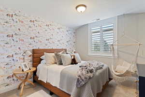 Bedroom featuring wallpapered walls, carpet, and an accent wall