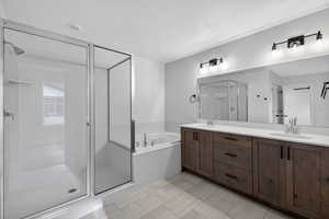 Bathroom with a stall shower, double vanity, a garden tub, and a textured ceiling