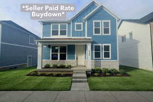 View of front of house with stone siding, a front lawn, covered porch, and board and batten siding