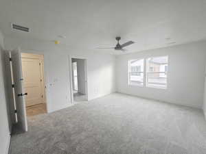 Unfurnished bedroom featuring light colored carpet, a ceiling fan, and a textured ceiling