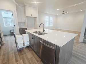 Two tone kitchen featuring dishwasher, light wood-type flooring, two tone color scheme, backsplash, and ceiling fan