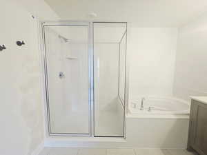 Full bath featuring a shower stall, a garden tub, vanity, and tile patterned flooring