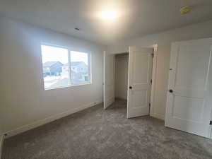 Unfurnished bedroom featuring dark carpet and baseboards