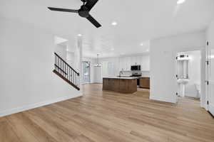 Kitchen with ceiling fan, an island with sink, light wood-type flooring, open floor plan, and dual tone cabinets