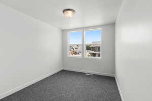 Empty room featuring dark colored carpet and baseboards