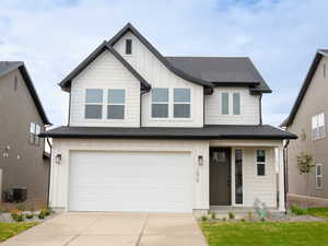 View of front of home with an attached garage, concrete driveway, board and batten siding, a front yard, and a porch