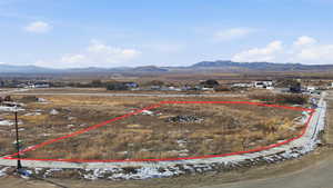 Aerial view of residential area with property boundaries highlighted and a mountainous background
