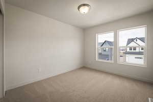 Carpeted empty room with baseboards and a textured ceiling