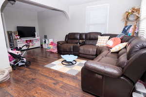 Living area with dark wood finished floors and arched walkways