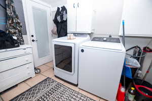 Laundry area featuring light tile patterned flooring, cabinet space, and washer and dryer