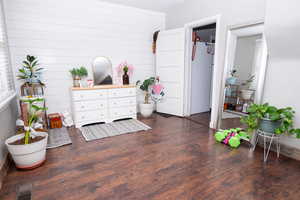 Sitting room featuring dark wood-style flooring and wooden walls