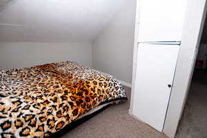 Bedroom with carpet floors and lofted ceiling